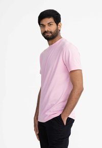 Roze T-shirt met korte mouwen van katoen, met een ronde hals en rechte zoom. Draag het met een zwarte broek, gepresenteerd tegen een witte achtergrond.