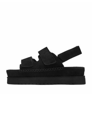 Czarna sandałka na platformie z dwiema regulowanymi paskami na rzepy na stopie oraz jednym wokół pięty, wyposażona w grubą wyściółkę podeszwy.