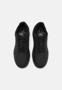 Baskets noires avec une tige synthétique lisse, lacets, détails perforés et semelle en caoutchouc texturée ; avec un logo sur la languette.