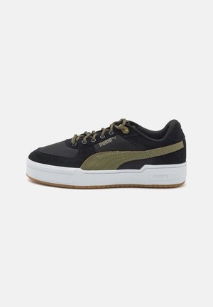 Zapatilla negra con acentos verde oliva, tejido texturizado y superposiciones suaves, media suela blanca y suela de goma color caramelo. Presenta cordones con estampado.