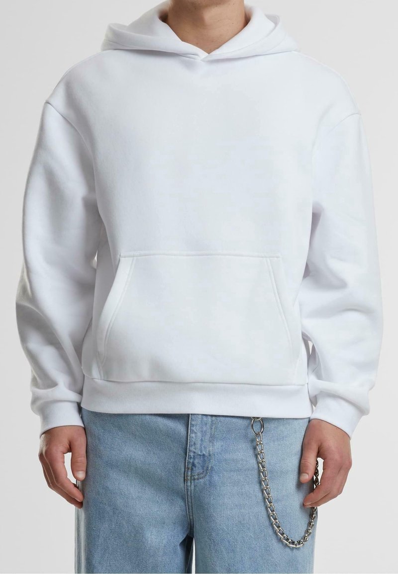 Felpa bianca con cappuccio realizzata in tessuto morbido. Presenta una tasca frontale, un cappuccio regolabile con cordini e polsini a coste. Abbinata a jeans blu chiaro e una catena.