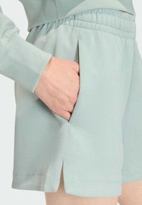 Light blue, elastic-waist shorts with side pockets and slits at the hem. Made of soft fabric, featuring a smooth texture and simple design.