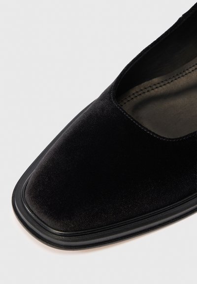 Juodas aksominis batelis su kvadratine nosimi, lygiu paviršiumi ir juodu guminiais padais. Viršutinė dalis turi elegantišką dizainą su žemu pjūviu.