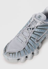 Αθλητικό παπούτσι σε ανοιχτό μπλε χρώμα με επάνω μέρος από δίχτυ, ασημί λεπτομέρειες, μαξιλαρωτή σόλα και μοναδικό κυματιστό σχέδιο με υφασμάτι�νες υφές.