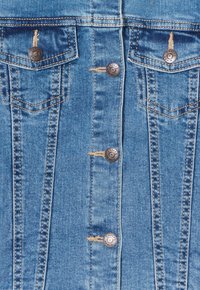 Hellblaues Denim-Westen mit einer Knopfleiste, zwei Brusttaschen, kupferfarbener Naht und Metallknöpfen. Abgenutzte Details in der Nähe der Knöpfe.