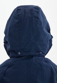 Marineblauwe hoodie met een gladde textuur, voorzien van drukknoopsluitingen bij de kraag en ronde stiksel op de achterkant van de capuchon.