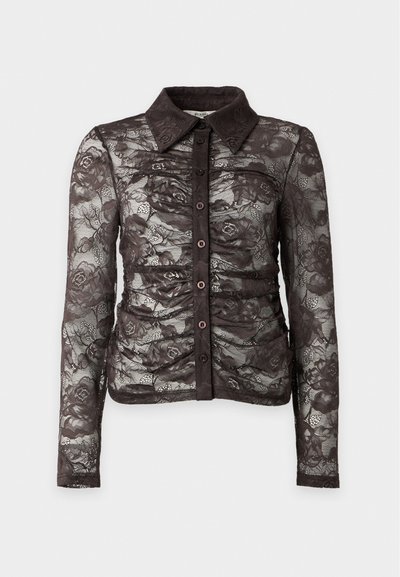 Blouse noire en dentelle à manches longues avec motif floral, fermeture boutonnée sur le devant, col pointu et détails froncés sur le torse.