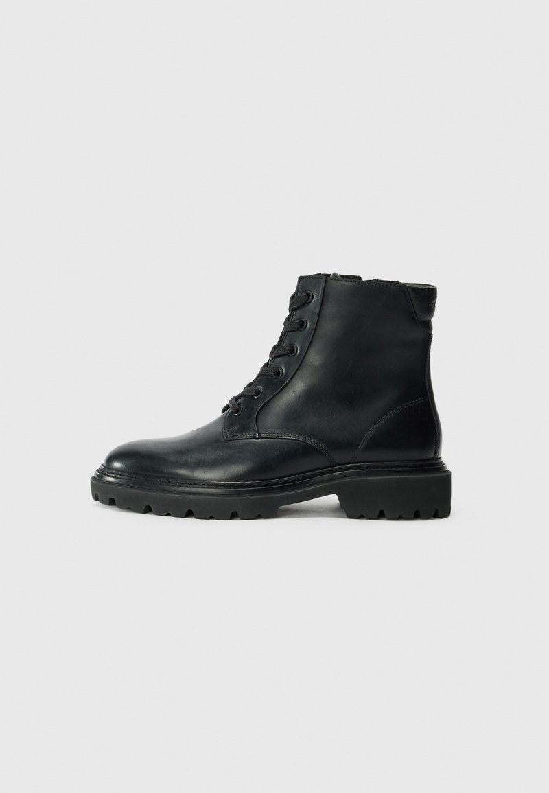 Mustad mustav nahast ankle boot, metallist nööridega, ümar varvas, kummist tald ja tekstureeritud aktsendid kandadel, et tagada parem haarduvus.