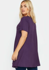 Välja violetti lyhythihainen paita rentona, jossa on metallisia yksityiskohtia edessä kuvioituna ja pyöristetty helma.