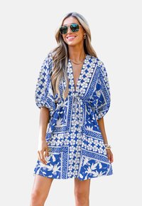 Abito blu e bianco con motivo floreale, scollatura a V profonda, maniche a sbuffo e vita regolabile con laccetto. Realizzato in tessuto leggero, adatto per l'estate.