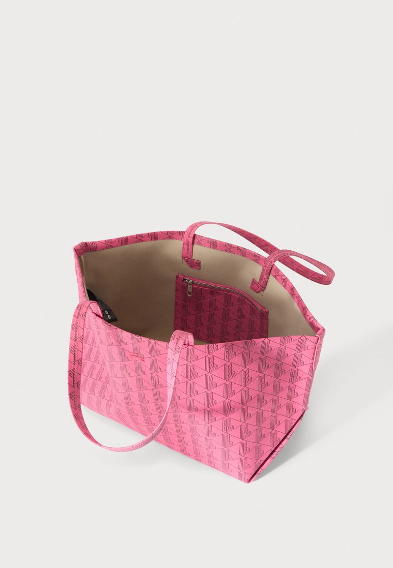 Pink tote bag with geometric pattern, open top showing beige interior and a matching pink zippered pouch inside.