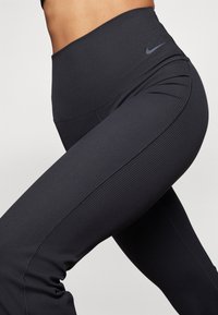 Leggings neri a costine con vita alta e logo Nike. Design elastico e aderente, caratterizzato da dettagli delle cuciture sottili e una texture liscia.