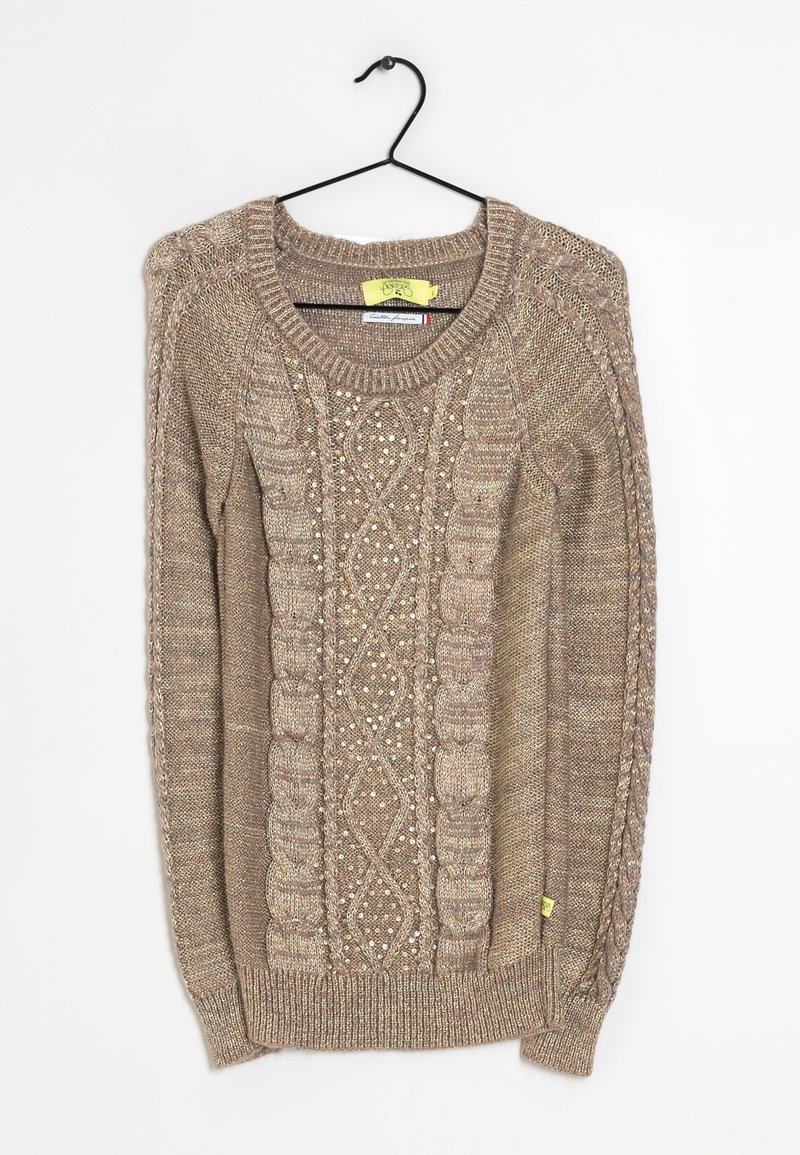 Stickad tröja i ljusbrunt med texturerade kabelmönster och små dekorationer. Har en ribbad krage och muddar, hängande på en svart krok.