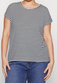 Camiseta de manga corta a rayas en azul marino y blanco. Escote redondo, corte relajado, tejido suave. Combinada con vaqueros azules para un look casual.