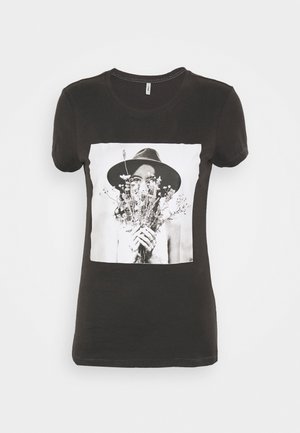 Černé tričko s krátkým rukávem, na kterém je velký černobílý motiv osoby držící květiny a nosící široký klobouk.