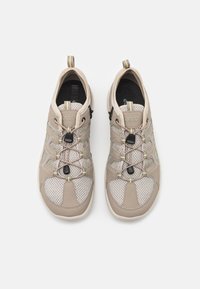 Scarpe sportive leggere beige con pannelli in rete, lacci elasticizzati e linguette. Presentano accenti testurizzati e una suola imbottita per il comfort.