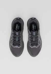 Grijze sportieve schoenen met een bovenwerk van mesh en synthetisch materiaal, veters, een gepolsterde kraag en "ASICS Ortholite" branding op de binnenzolen.