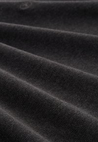 Czarny materiał o gładkiej strukturze, z delikatnymi diagonalnymi fałdami i drobnym splotem. Minimalistyczny design bez ozdób.
