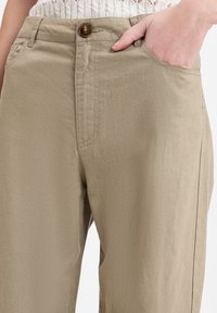 Kaarse katoenen broeken met een gladde textuur, voorzien van een knoopsluiting, zijzakken en een rechte snit.