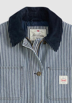 Stribet blå og hvid jakke med krave i navy kordfløjl, guld lynlås og lomme med klap. Mærket synligt med "Levi Strauss" branding.