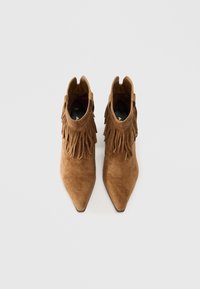 Botine din suede maro până la glezne, cu detalii franjurate, design cu vârf ascuțit și o textură netedă. Interiorul prezintă o branț negru.