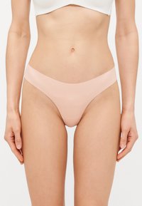 Ljusrosa stringtrosor gjorda av glatt, stretchigt tyg, med en låg midja och en minimalistisk, sömlös midjeband.