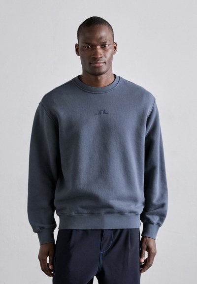 Sweatshirt azul escuro feito de tecido macio, com decote redondo, punhos canelados e um pequeno logótipo bordado no peito.
