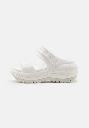 Hvid platformsandal med justerbar rem, perforerede detaljer og tyk, tekstureret sål for ekstra højde og greb.