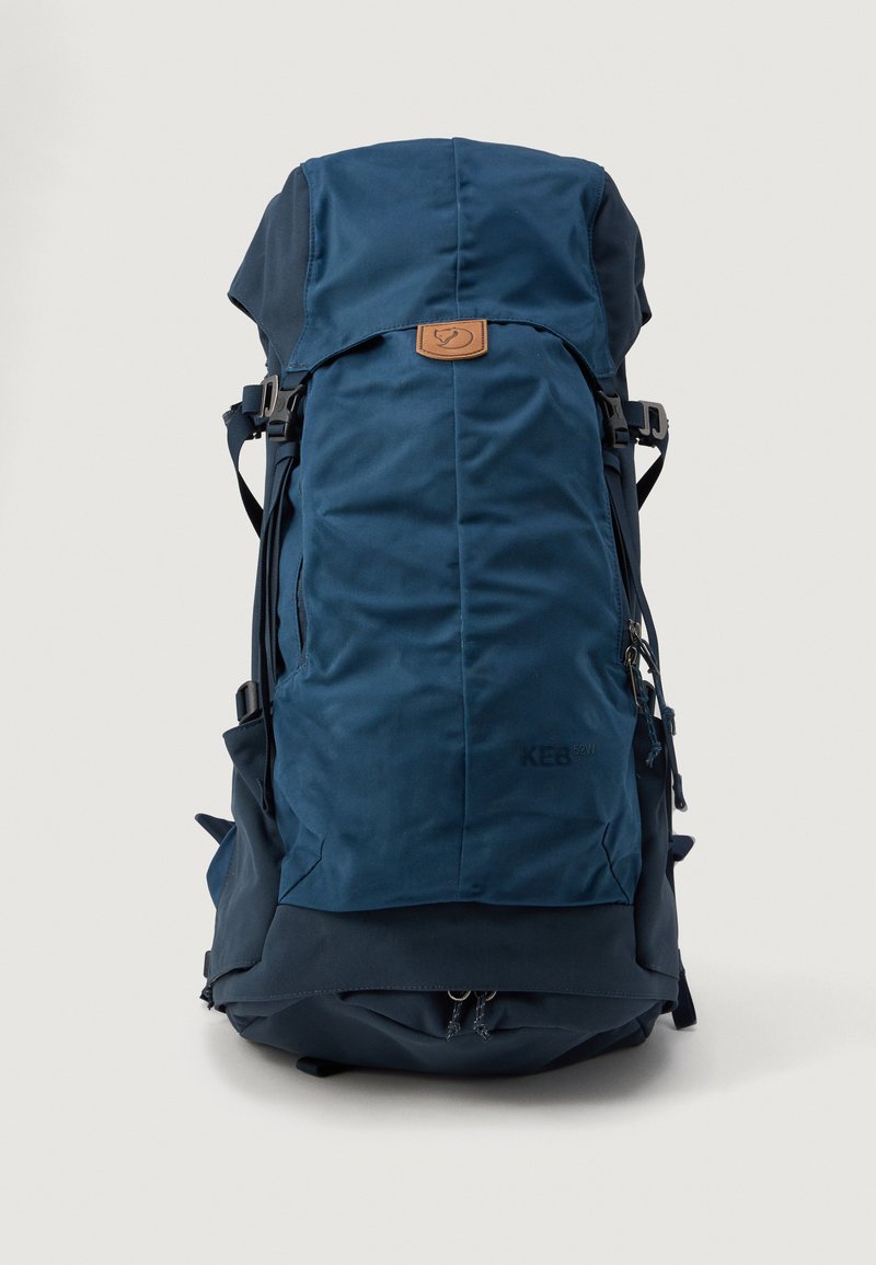 Mochila azul marinho com fecho tipo roll-top, detalhes em couro e bolsos laterais com zíper; feita de um tecido durável e texturado.