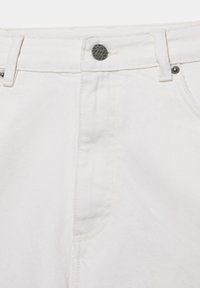 Gros plan sur un jean en denim blanc montrant la ceinture avec passants, une fermeture à bouton en métal et les détails de couture au bord de la poche avant.