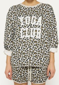 Sweatshirt con stampa leopardata e testo bianco "YOGA CLUB". Presenta maniche lunghe e una vestibilità rilassata, realizzato in tessuto morbido con polsini arrotolati.
