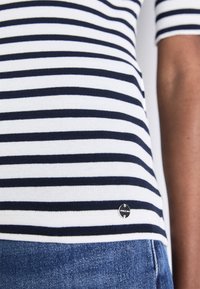 Navy und weiß gestreiftes, tailliertes T-Shirt mit kurzen Ärmeln und geripptem Material. Verfügt über ein kleines schwarzes Logo-Tag nahe dem unteren Saum.