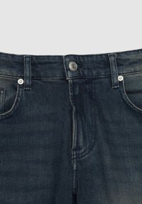 Jeans de mezclilla azul oscuro con corte recto, cinco bolsillos y herrajes en tono plata. La tela presenta un ligero desvanecimiento y tiene una textura suave.