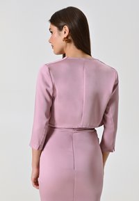 Abito di raso rosa con maniche a tre quarti, silhouette aderente e un sottile dettaglio della cucitura posteriore. Tessuto liscio con una finitura elegante.