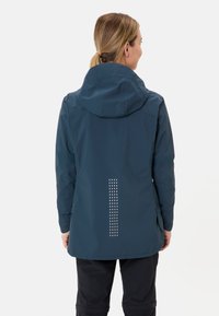 Waterdichte marineblauwe jas met een capuchon, voorzien van reflecterende stippenpatronen op de achterkant en verstelbare manchetten. Gemaakt van een lichtgewicht materiaal.