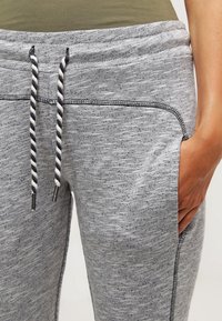 Grå sweatpants med en texturerad tyg, med dragsko i midjan som har svart och vitt randiga snoddar samt sidofickor.