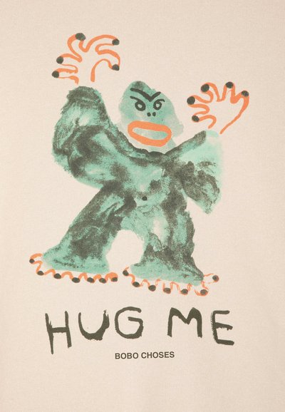 Gorille verte dessin animé avec de grandes mains et pieds entourés d'orange, visage en colère, au-dessus du texte "HUG ME" et "BOBO CHOSES" sur fond beige.