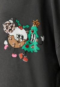 Grauer Stoff mit einem verspielten Grafikdesign eines dekorierten Donuts und eines Weihnachtsbaums, verziert mit Pailletten und bunten Akzenten.