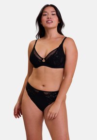 Ensemble de lingerie noir comprenant un bralette en dentelle transparente avec un détail en trou de serrure et une culotte taille haute assortie avec des accents en dentelle.