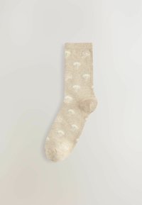 Knit-sukka beige-värissä, jossa on pehmeä rakenne ja hienovarainen sienikuosi vaaleassa kermanvärissä. Vakiosukkapituus ja vahvistettu varvas.