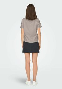 Grå bomulls-T-shirt med kort ärm, kombinerad med en mörk denimkjol. Outfiten fulländas med vita sneakers.