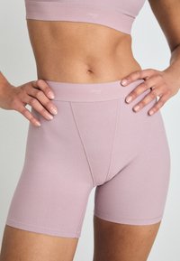 Shorts sportivi rosa chiaro realizzati in tessuto elastico, caratterizzati da una vita senza cuciture e una vestibilità aderente con cuciture minime.