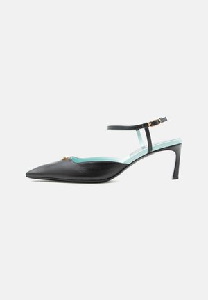 Black pointed-toe heeled shoe with ankle strap, gold buckle, and light blue inner lining, shown in side profile on white background.