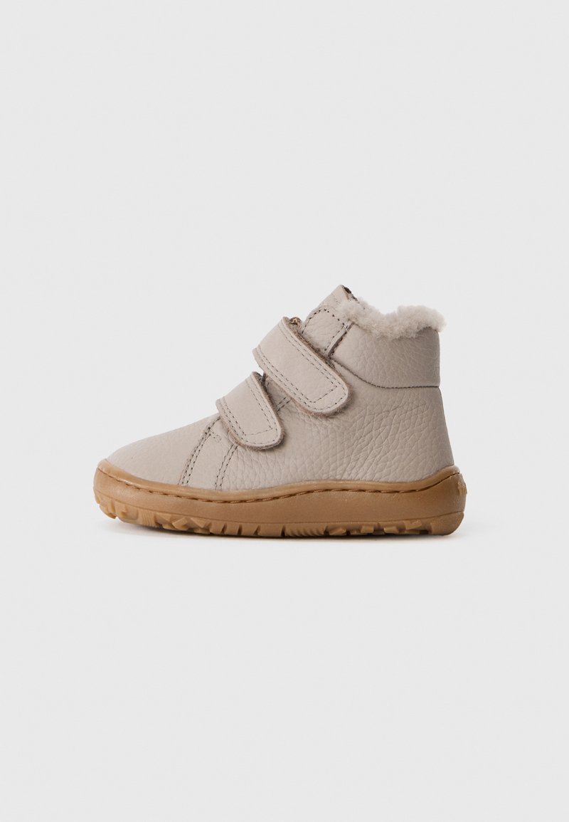 Botas de tobillo de cuero beige con dos correas de velcro, acabado texturizado y cuello de pelo; suela de goma con patrón de tracción.