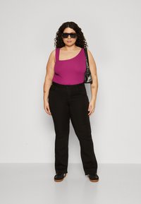 Top fucsia de un solo hombro, pantalones ajustados negros, bolso negro de mano, gafas de sol negras, tejido texturizado, estilo casual, pose de pie.