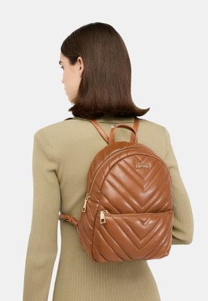 Mochila de cuero marrón acolchada con asa superior, correas ajustables y bolsillo delantero con cremallera. Presenta un detalle de logo en relieve.