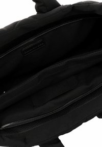 Black backpack with quilted fabric, zippered compartments, smooth lining, and a textured base. Features contrasting stitching and leather accents.