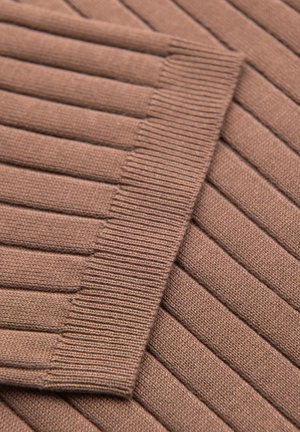 Gros plan sur un tissu tricoté côtelé marron avec bord plié montrant des motifs texturés verticaux et horizontaux.