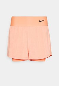 Shorts de mujer de Nike en rosa claro con una cinturilla en melocotón contrastante. Presenta una capa exterior suelta y forro interior, textura suave y logo de acento.