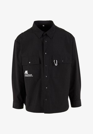 Schwarzes Langarmhemd aus Baumwolle mit Knopfleiste, zwei Brusttaschen und einem weißen Logo. Verfügt über einen Karabinerhaken an einer Tasche.